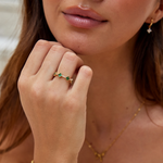 Annika – Anillo dorado con detalles florales y elemento de esmeralda.