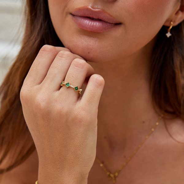 Annika – Anillo dorado con detalles florales y elemento de esmeralda.