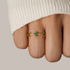 Annika – Anillo dorado con detalles florales y elemento de esmeralda.