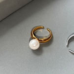 Ida – Golden ring with a smooth surface and pearl accent.
