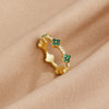 Annika – Anillo dorado con detalles florales y elemento de esmeralda.