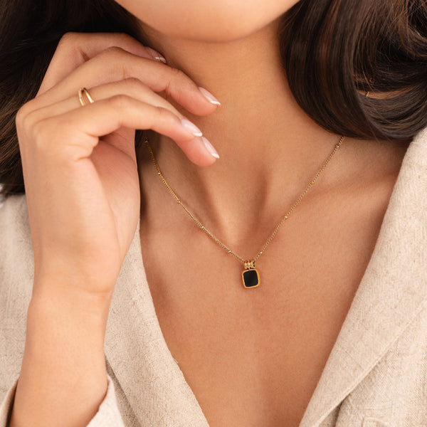 Selina – Collar dorado con piedra oscura.
