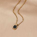 Selina – Collar dorado con piedra oscura.